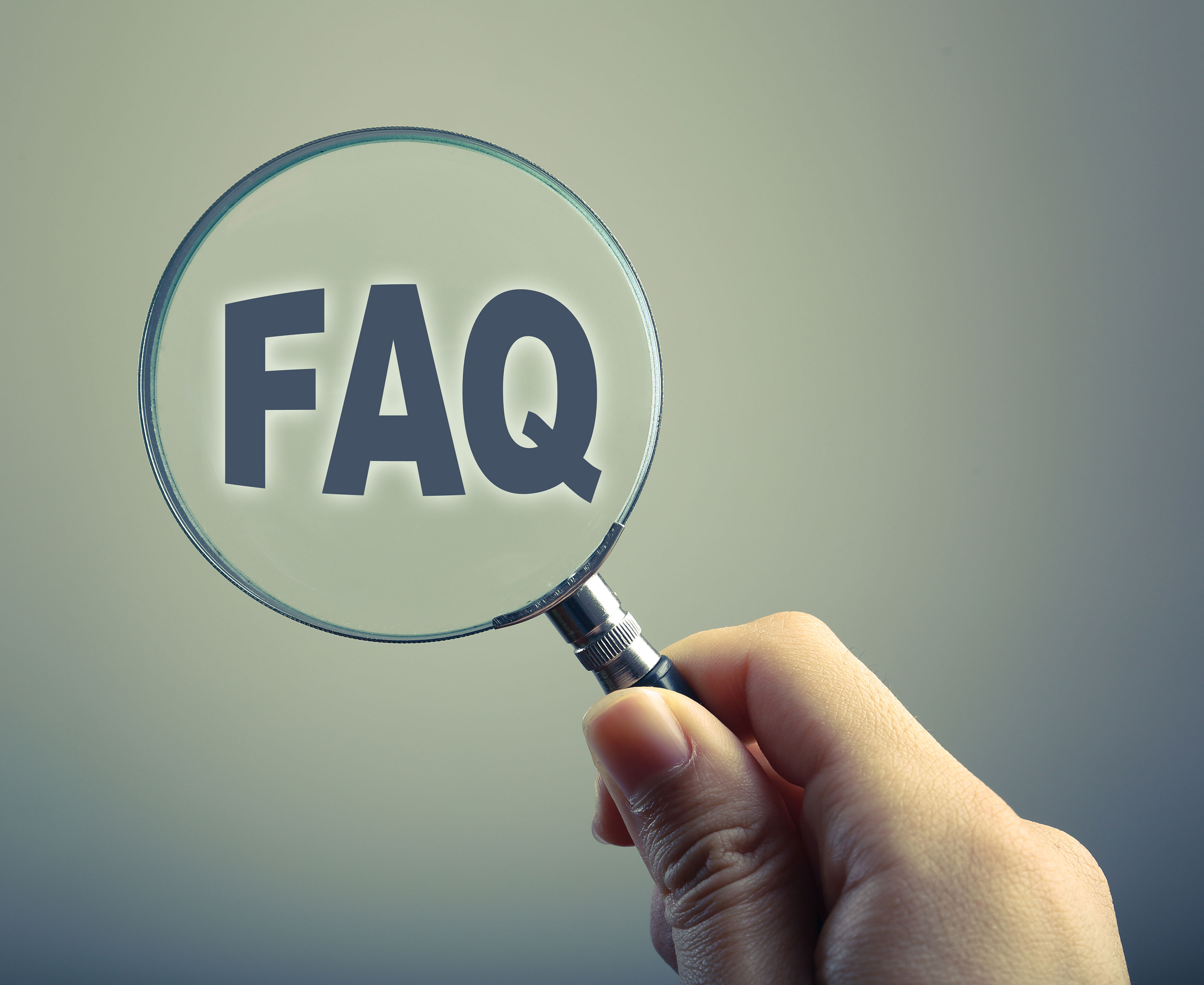 Hånd der holder en lup foran ordet FAQ