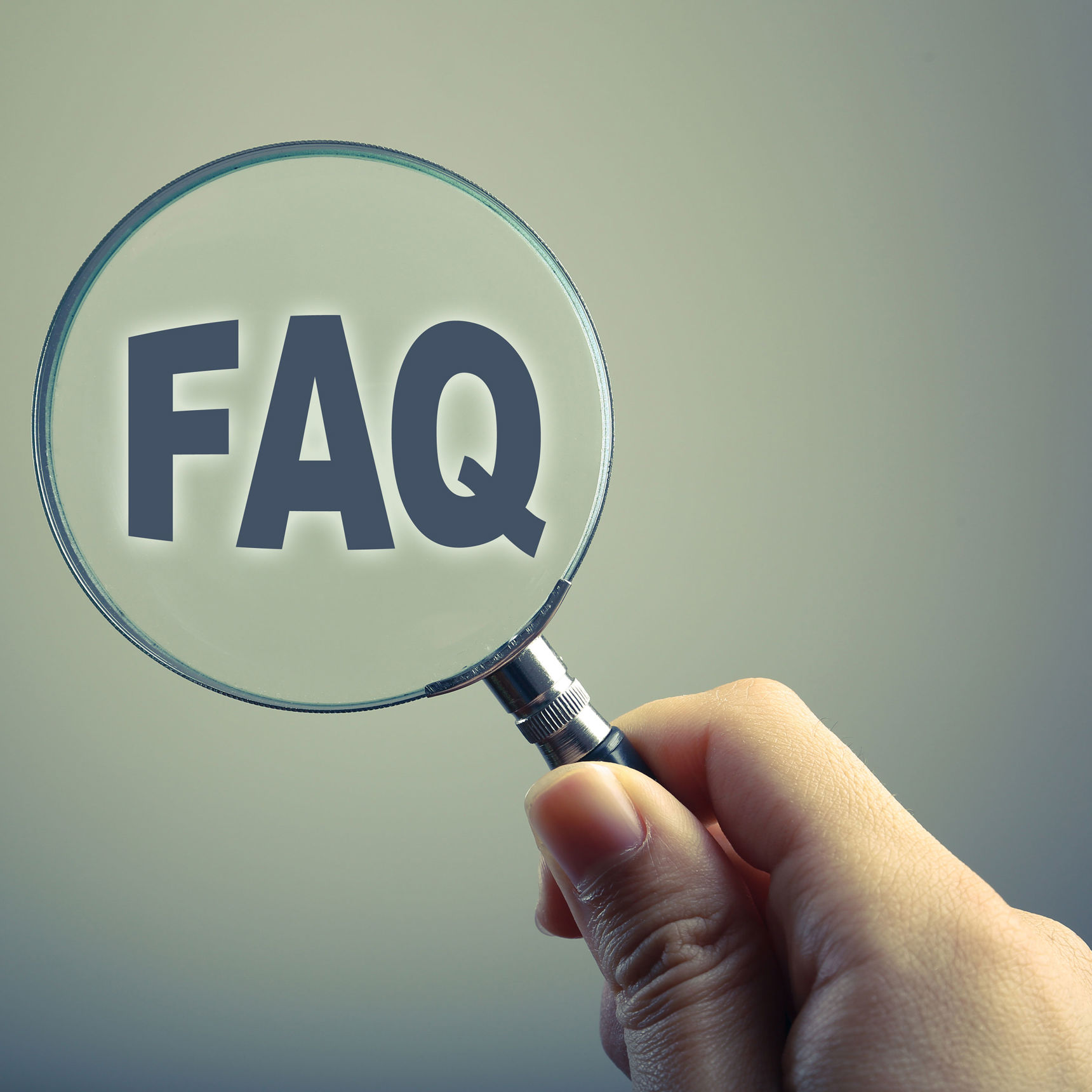 Hånd der holder en lup foran ordet FAQ